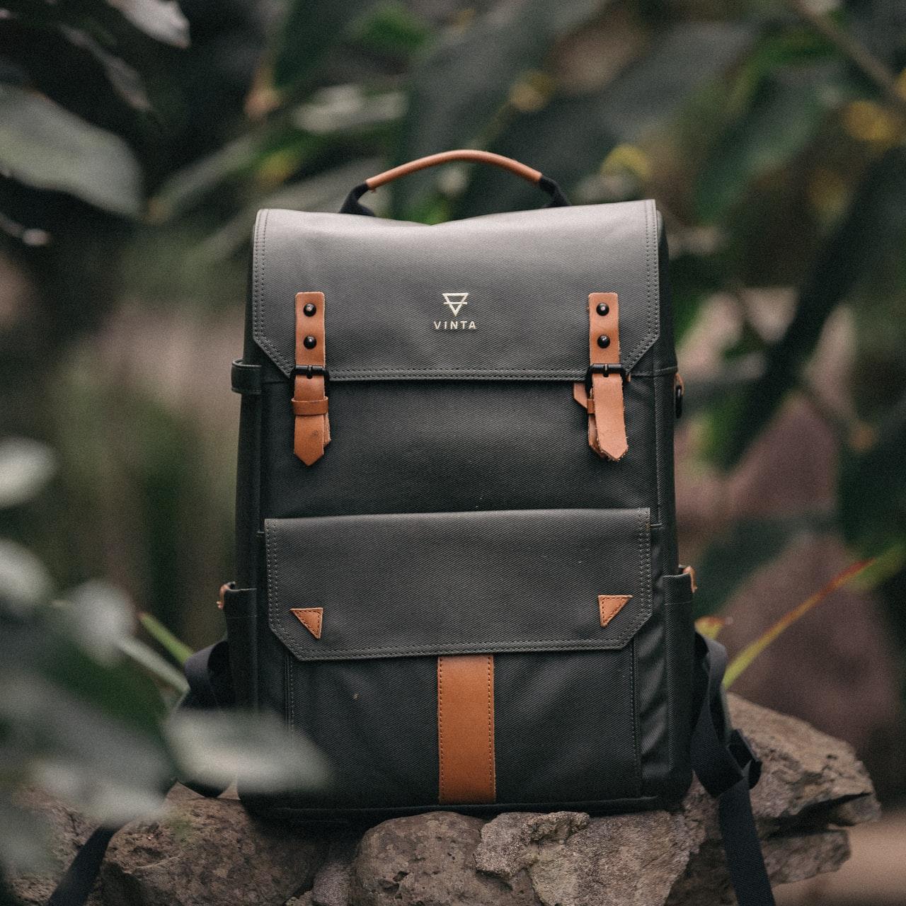 selective focus photography of black and brown leather backpack on rock