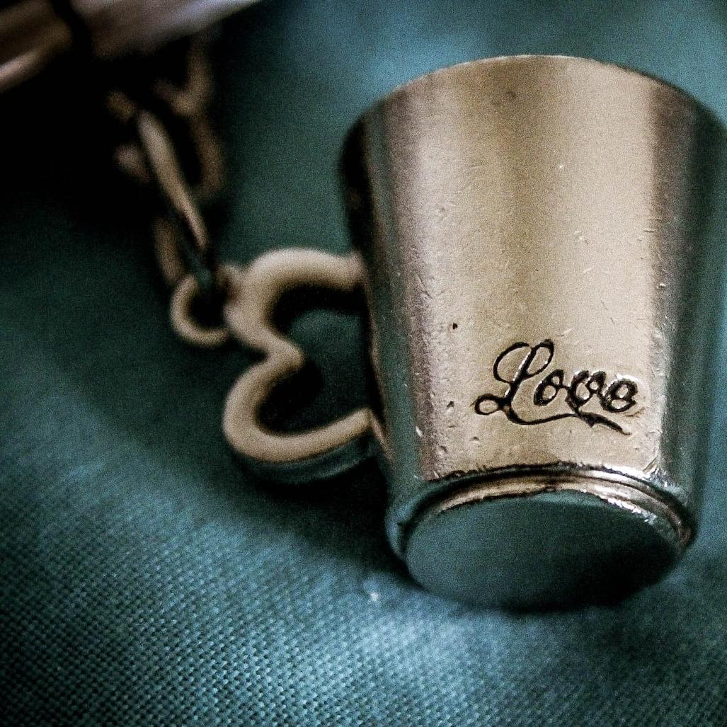 closeup photo of silver-colored love mug pendant